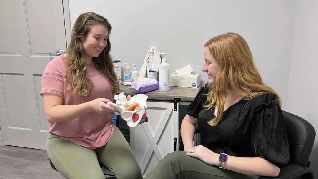 Pelvic floor physical therapist teaching patient about the pelvic floor using a pelvic model.